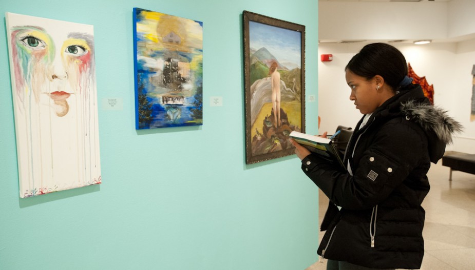 Student examines artwork in gallery